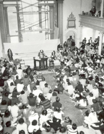 Allen Ginsberg reads in St. Mark's Church Sanctuary, ca. 1976 (Maureen Owen sits on the steps to his right). Courtesy The Poetry Project.